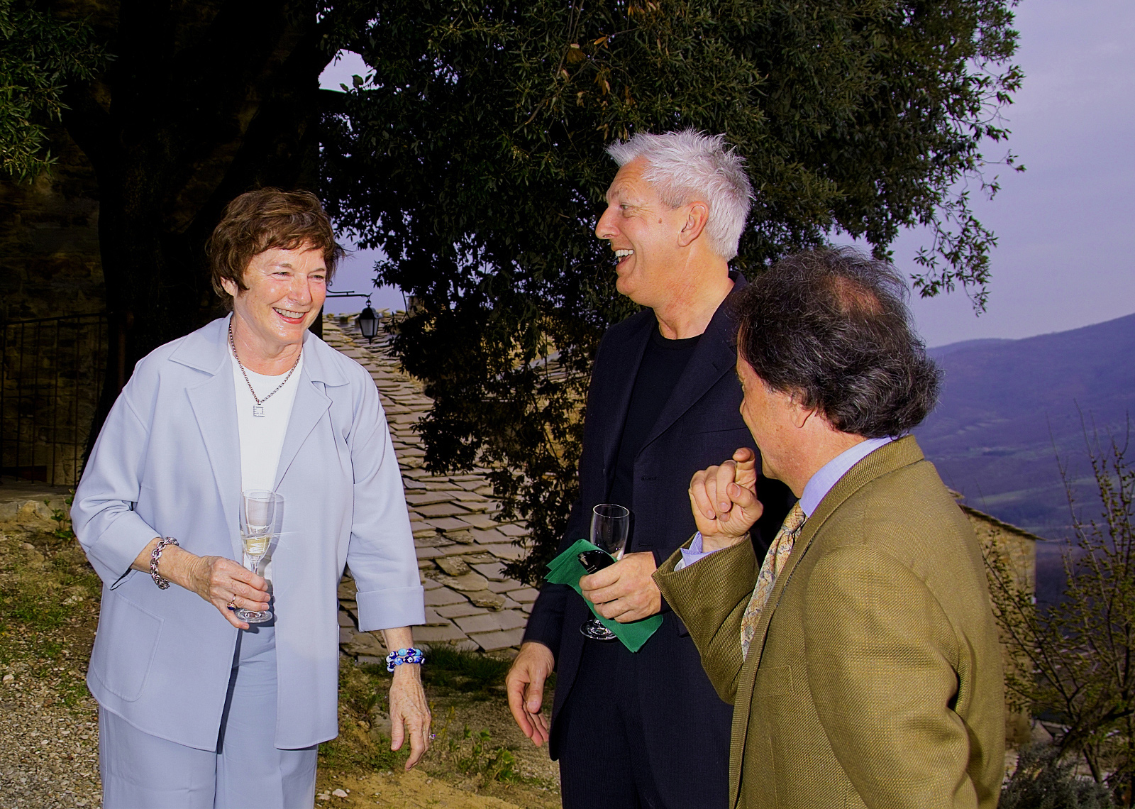 The photo shows Frances Mayes, Edward Kleinschmidt Mayes and Fulvio Di Rosa laughing together at the
                  opening ceremony of Borgo di Vagli